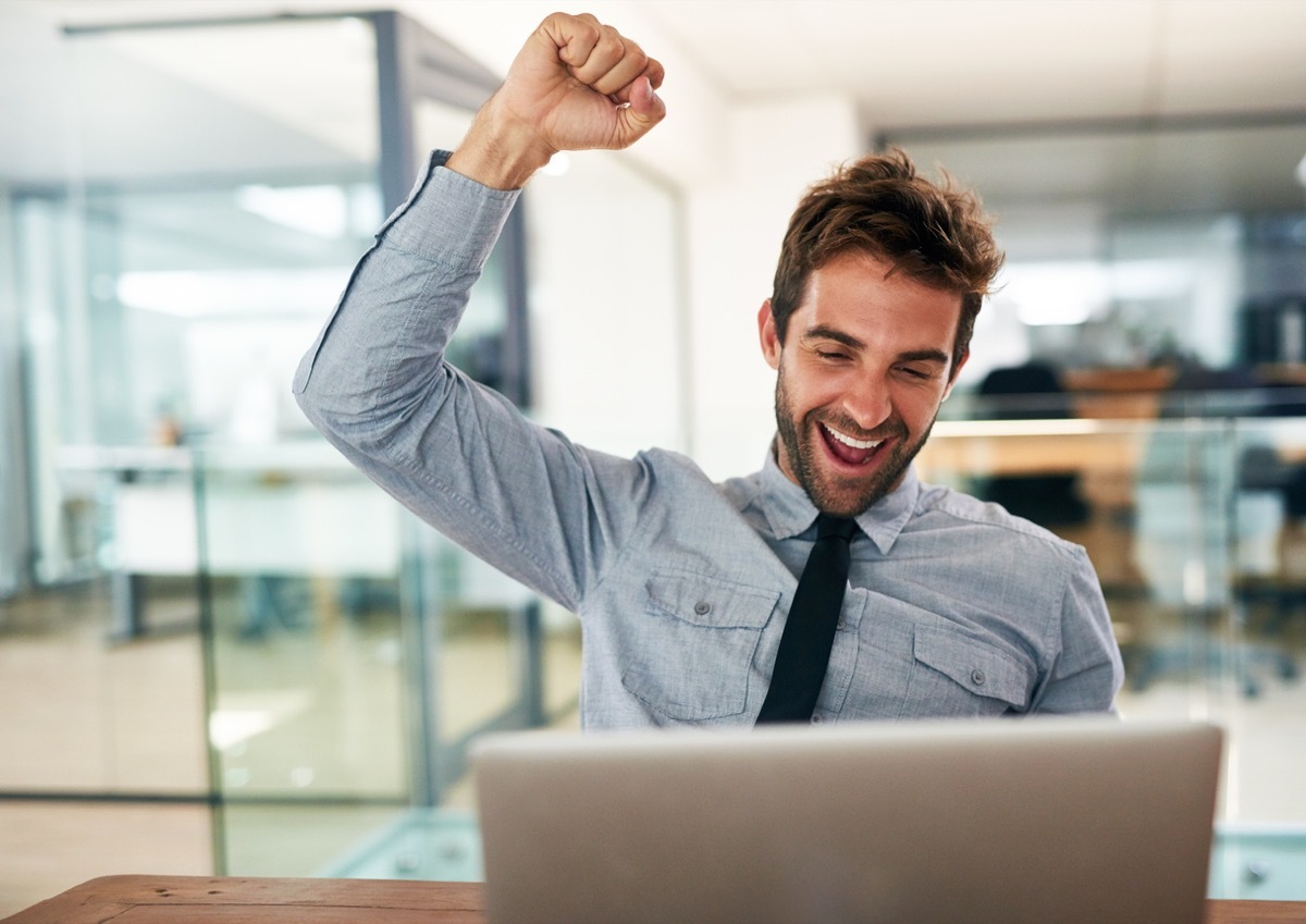 white man cheering at his laptop in an office