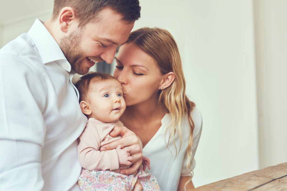 white mother and father holding and kissing newborn baby girl