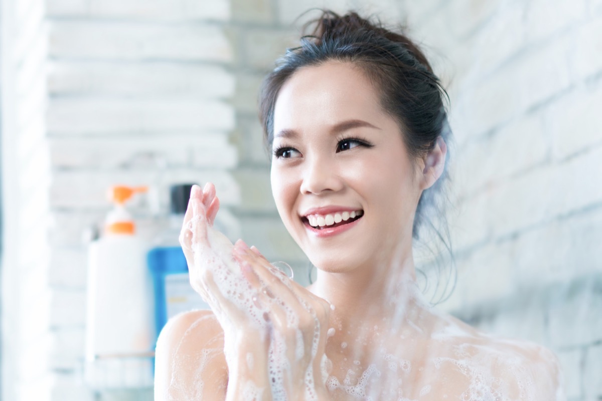 Woman is taking a shower in the bathroom she is rubbing soap.