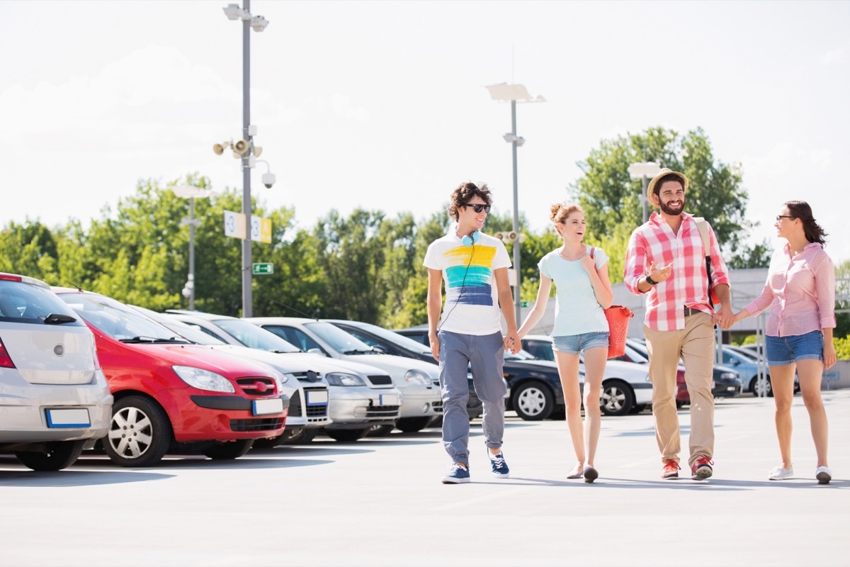 Two happy couples holding hands and walking together through a parking lot