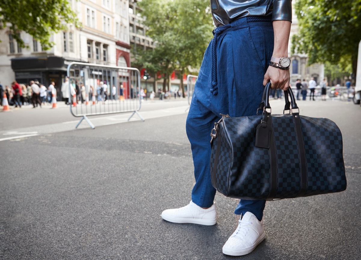 man wearing drop-crotch sweats with a gucci duffel