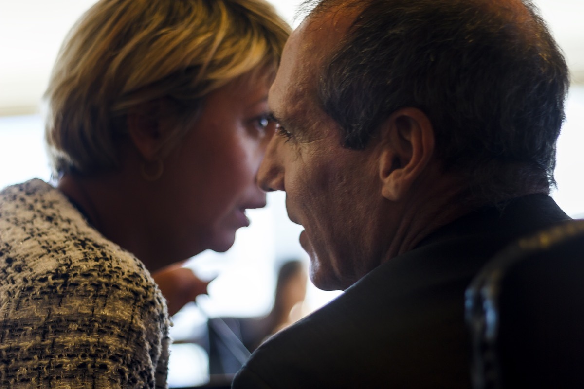 Businesswoman whispering to her colleague around a conference table