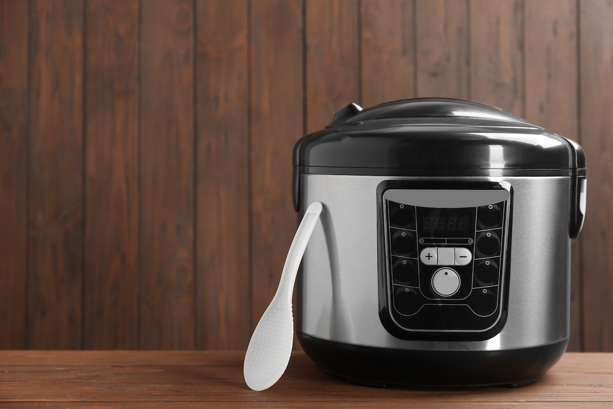 Modern powerful multi cooker on table against wooden background