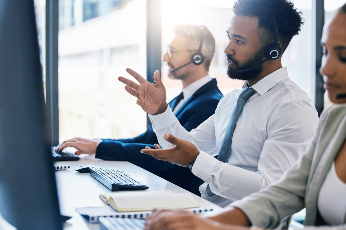 Call center, customer care and support with a man consultant in a headset working on a computer in his office.