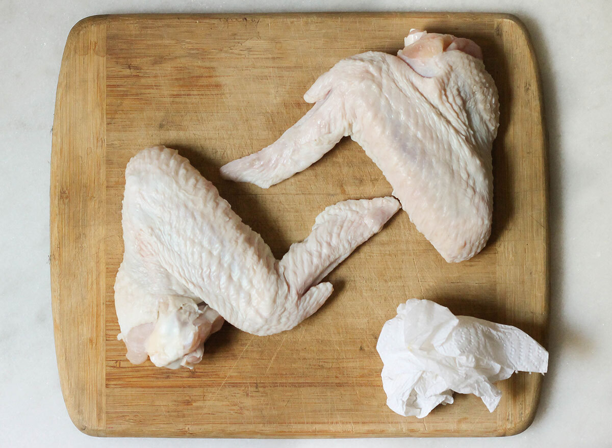 Patting down turkey wings with a paper towel