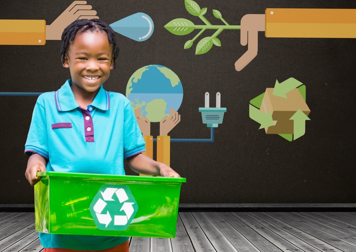 child smiling and holding recycling bin