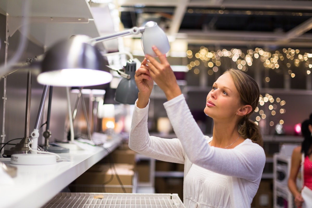 woman inspecting lamp at store