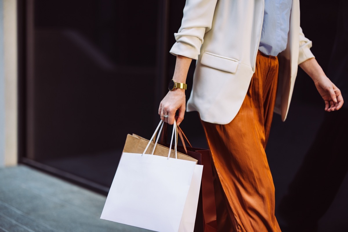 Unrecognizable businesswoman carrying paper bags while walking at the city street.