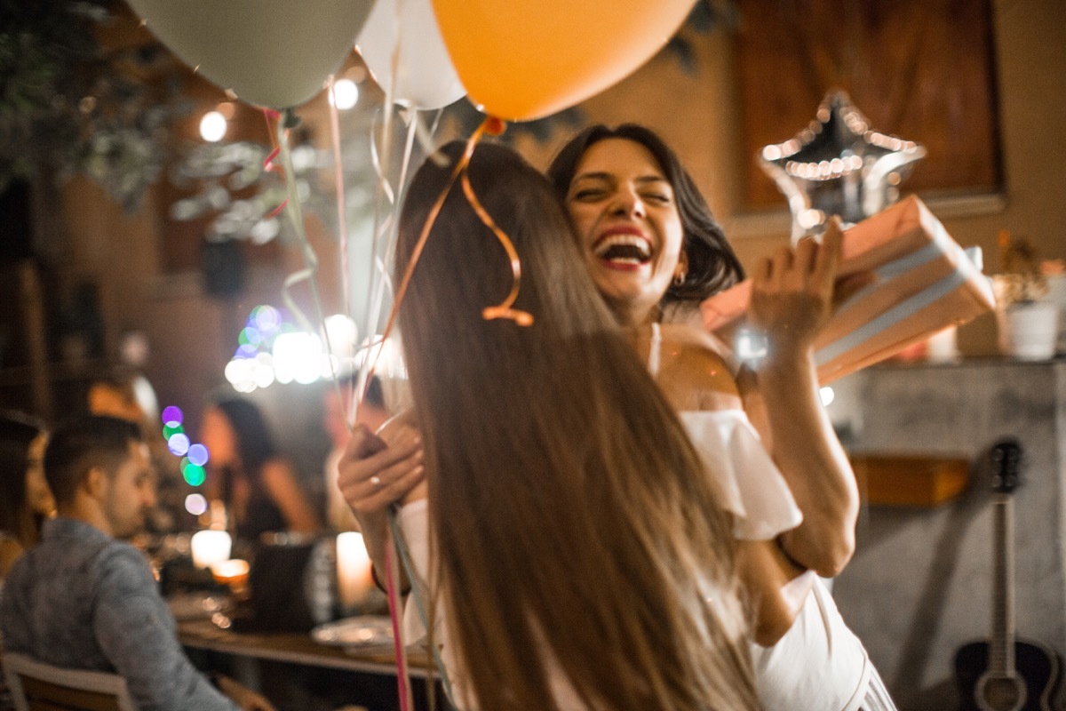 Woman welcoming guest on her birthday dinner party and receiving gifts