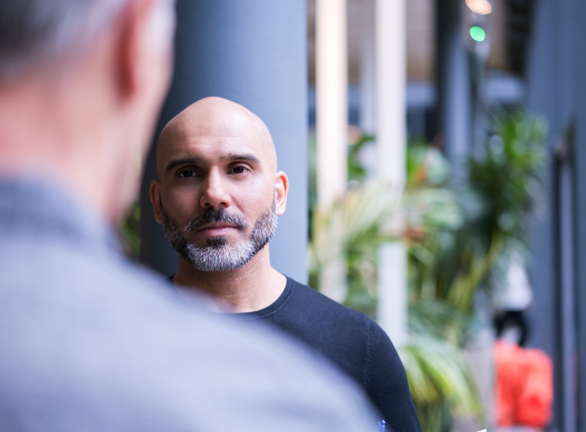 mature businessman looking at colleague in creative office. Male professionals are working at workplace. Focus is on mature businessman.