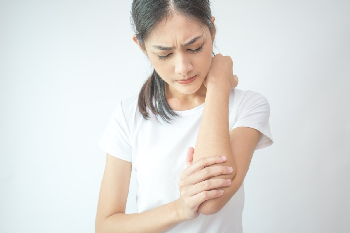 Woman holding and examinging her arm in discomfort