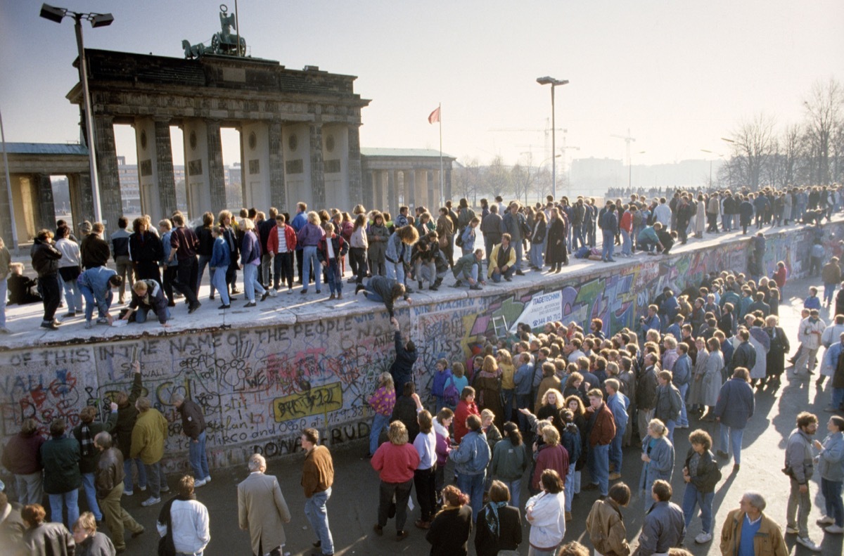 ossis and wessis dancing on top of the berlin wall in 1989