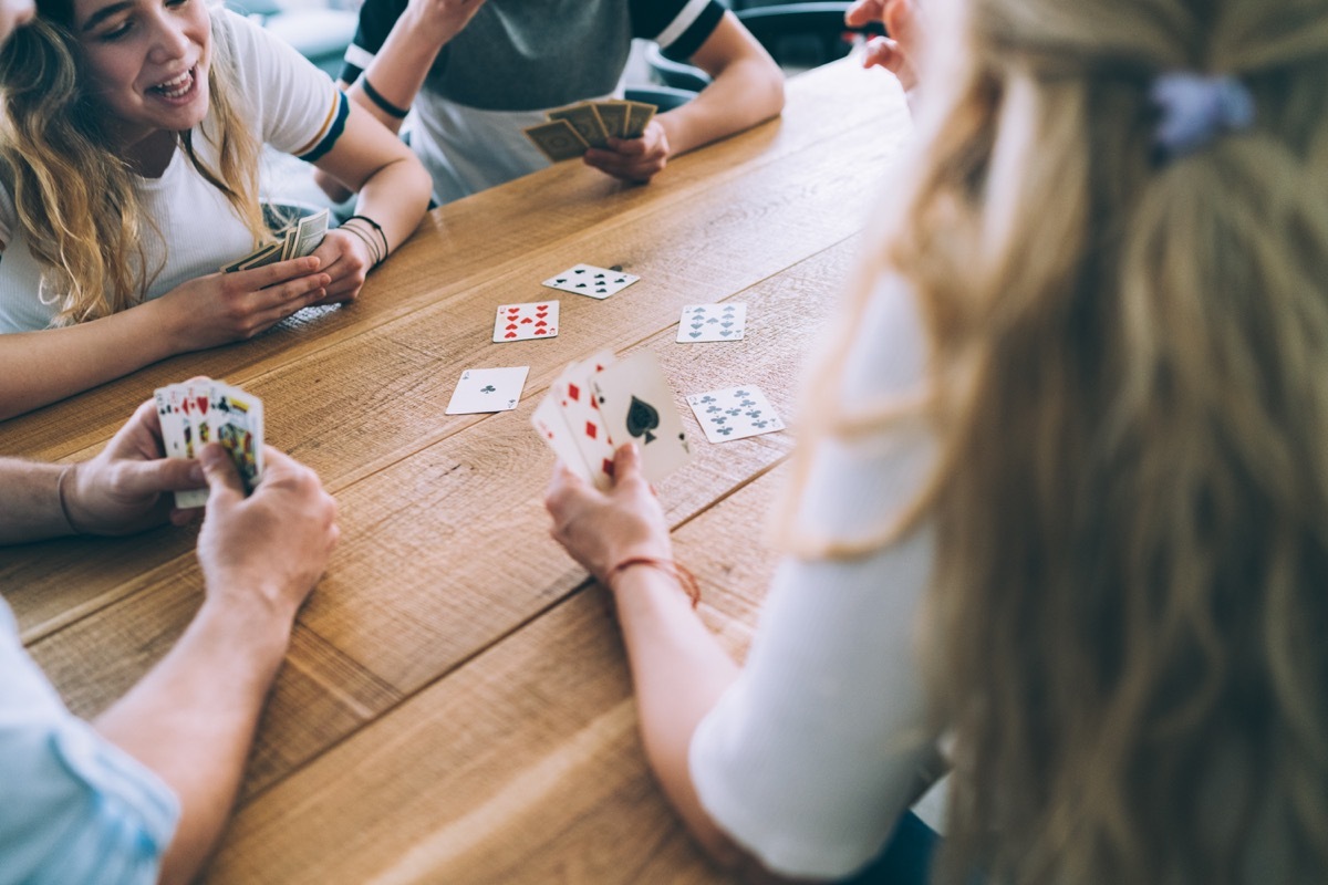 teenage kids playing a round of cards