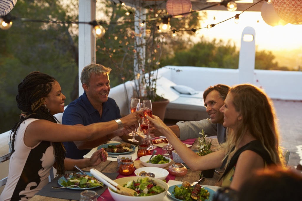 two middle aged couples having dinner at sunset