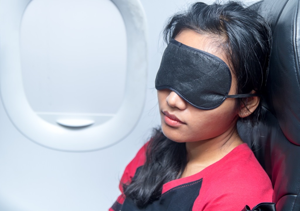 Woman sleeping on a plane with a face mask.