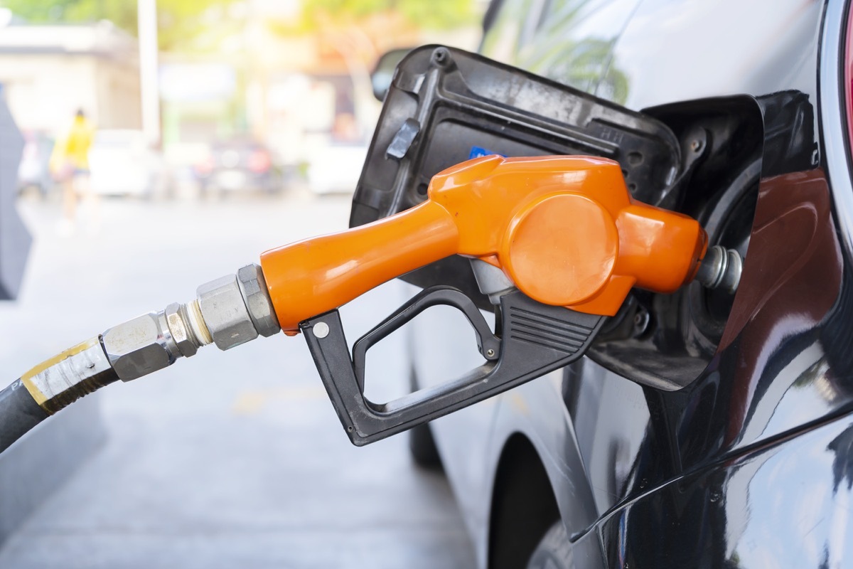 fuel nozzle filled car with fuel, car being filled gasoline at gas station, Pumping gasoline fuel in black car at gas station , Gas pump nozzle.