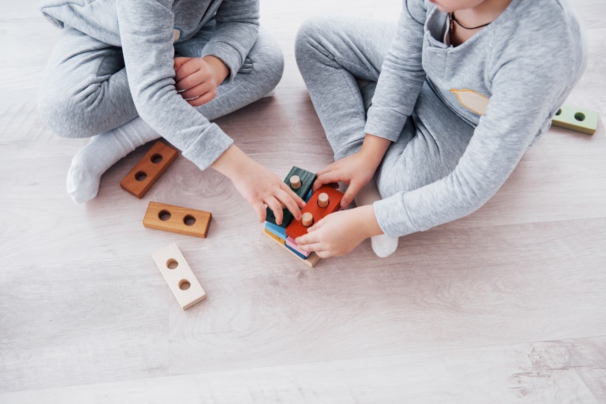 Children play with a toy designer on the floor of the children's room. Two kids playing with colorful blocks. Kindergarten educational games. - Image