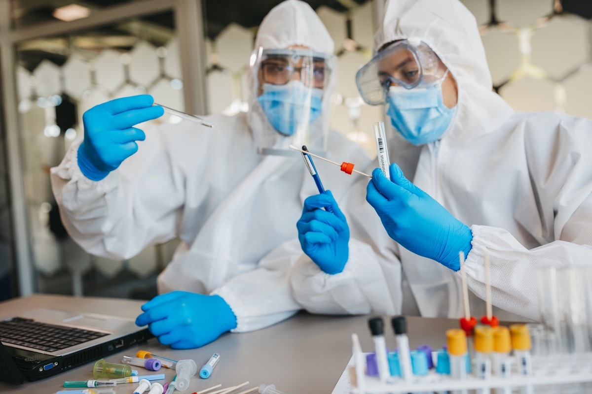 Two medical workers working with covid19 samples. Both are dressed in full protective suits.