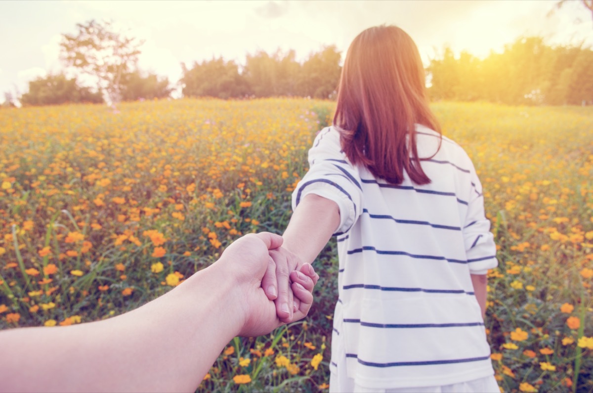 Woman leading man through field of flowers