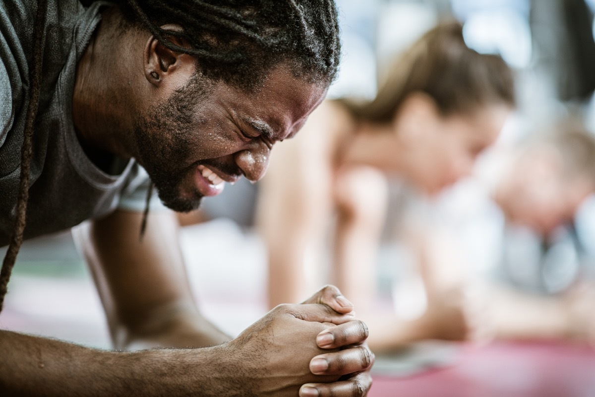 close up of black man sweating while doing a stretch at the gym