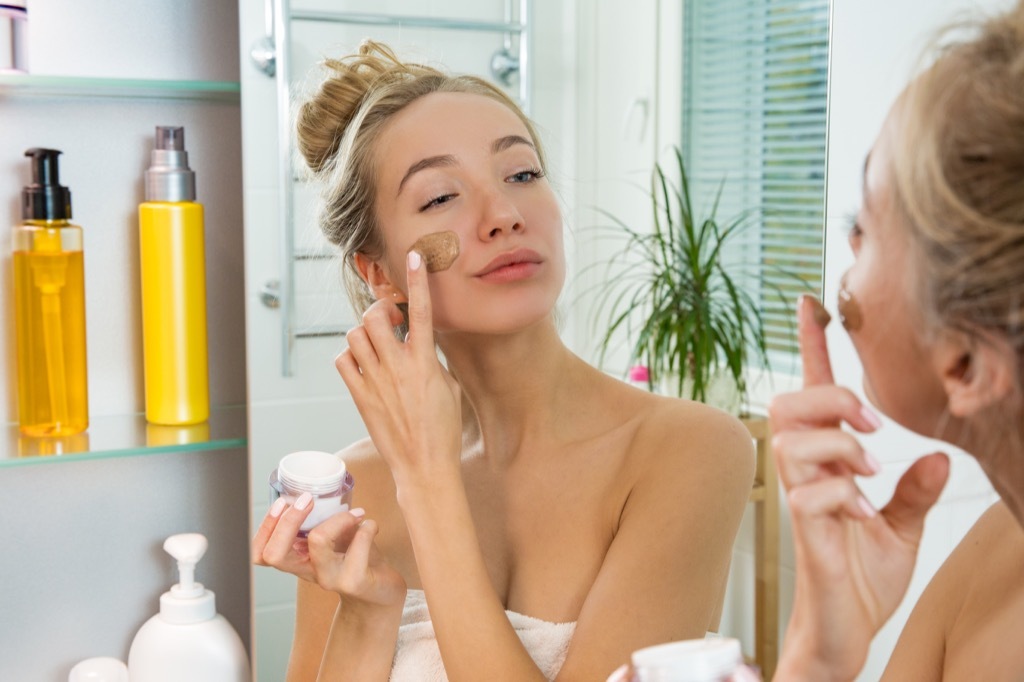 woman putting on makeup in mirror