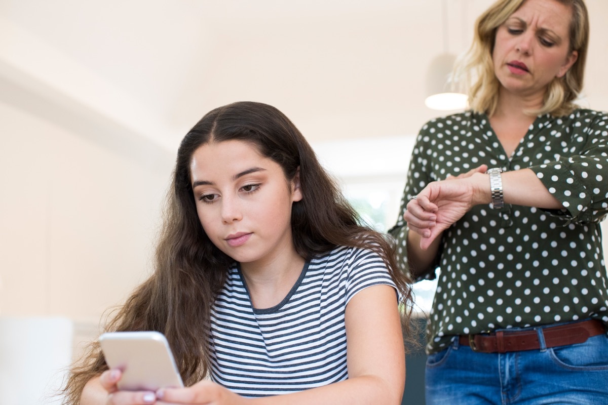 mother scolding teenage daughter for still being on her mobile phone