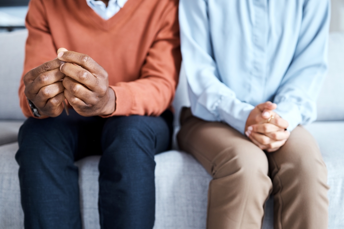 Two people sitting with nervous hands, one has hands folded, the other is fidgeting with their hands