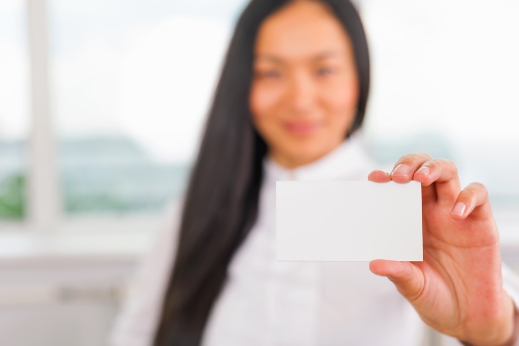 Businesswoman handing over a blank business card.