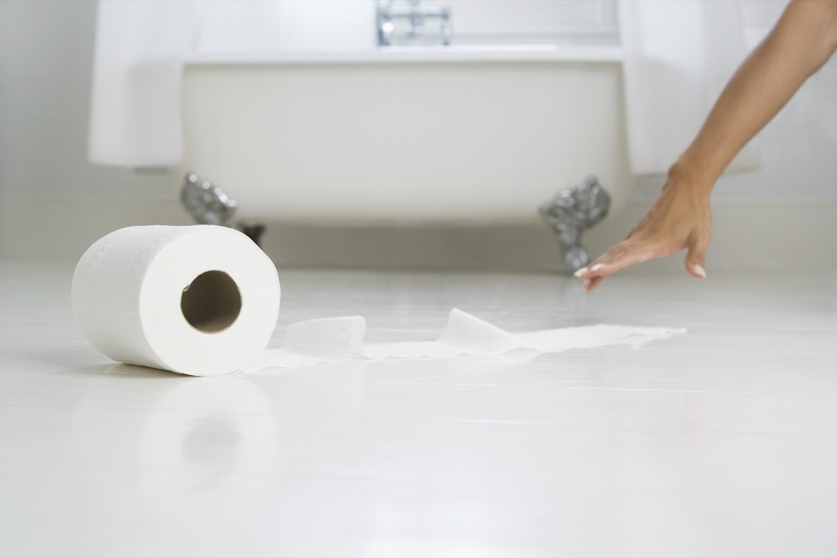 woman's hand reaching tissue paper in bathroom