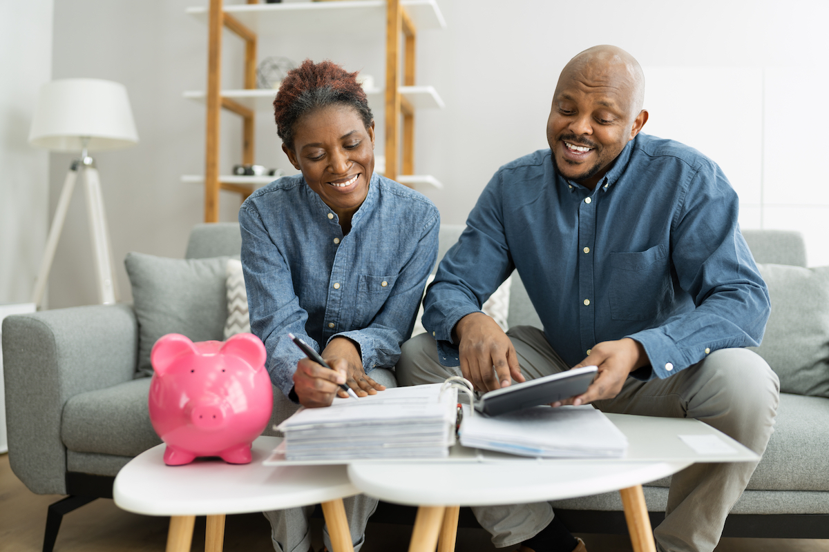 Middle-aged couple sitting on their couch planning for retirement with a pink piggy bank on the table