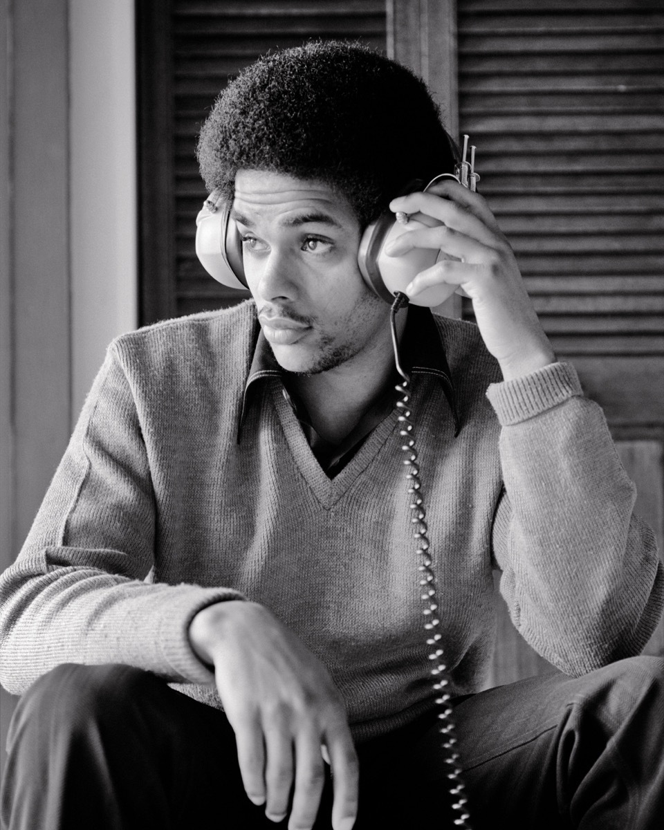 1970s AFRICAN-AMERICAN TEENAGE YOUNG MAN LISTENING TO MUSIC USING STEREO HEADPHONES