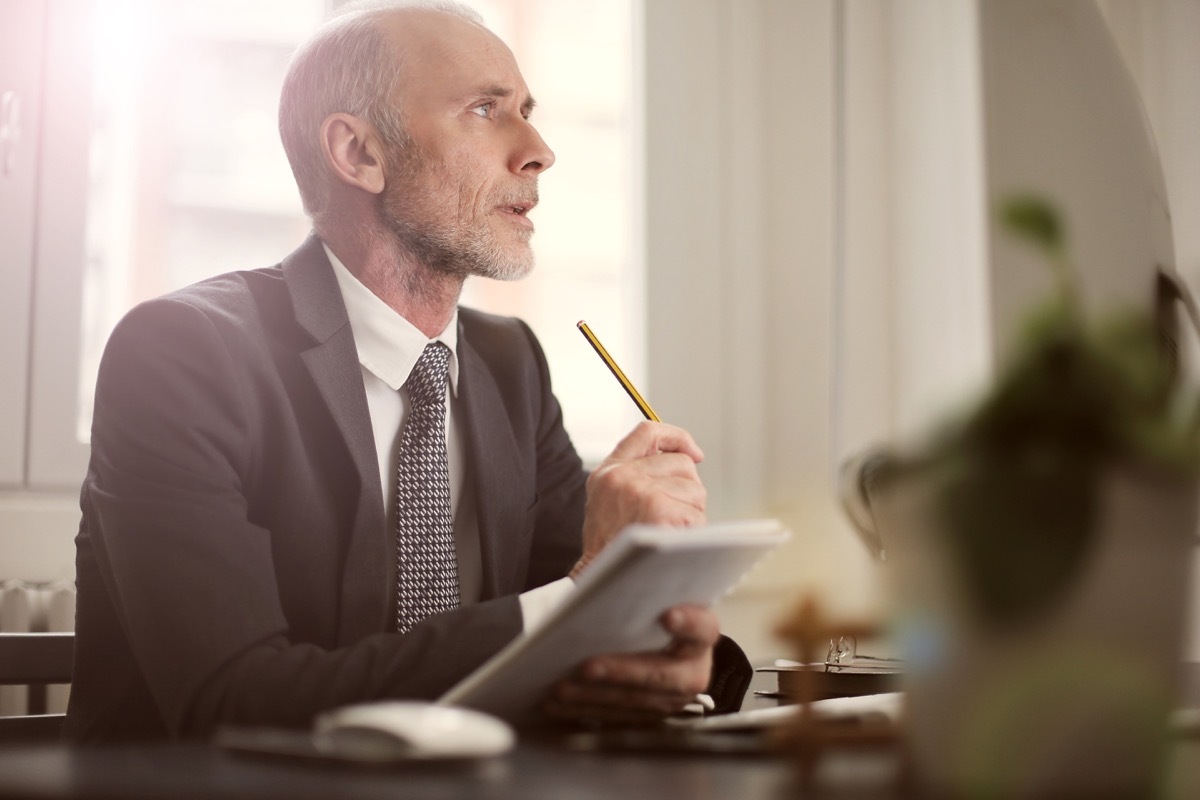 a man sitting at a desk and writing while thinking