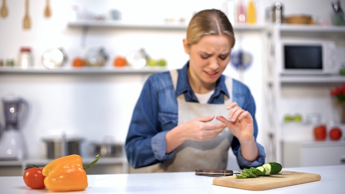 Female cut finger while slicing cucumber, accident in kitchen, household injury