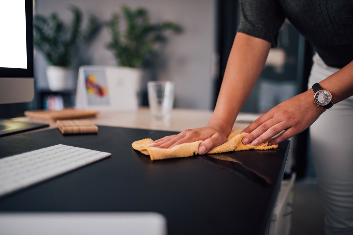 businesswoman wiping her work desk, close-up.