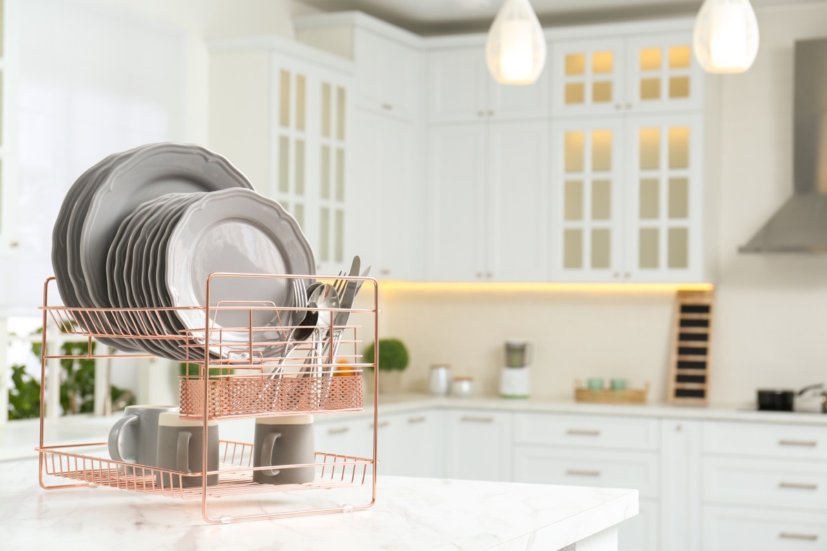 Drying rack with clean dishes on table in kitchen. Space for text