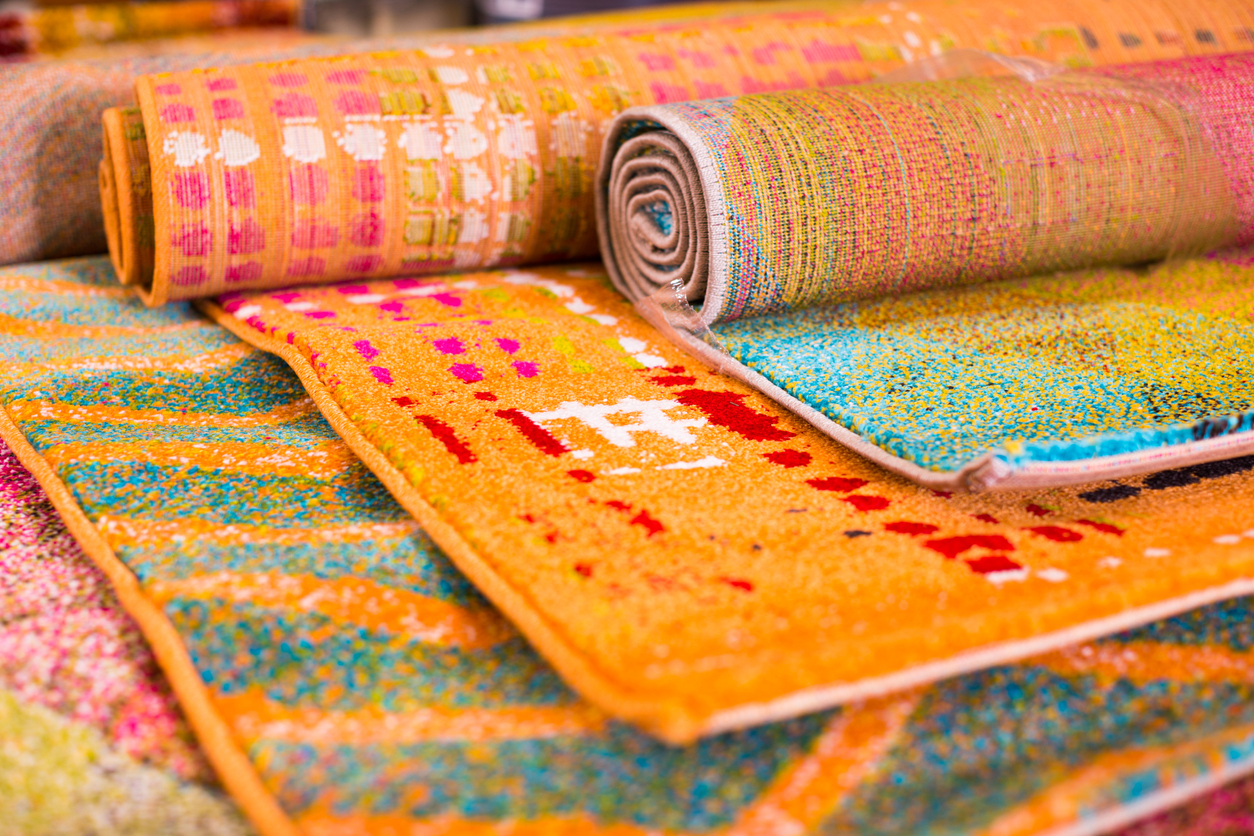 A variety of brightly colored rugs rolled up on display next to each other