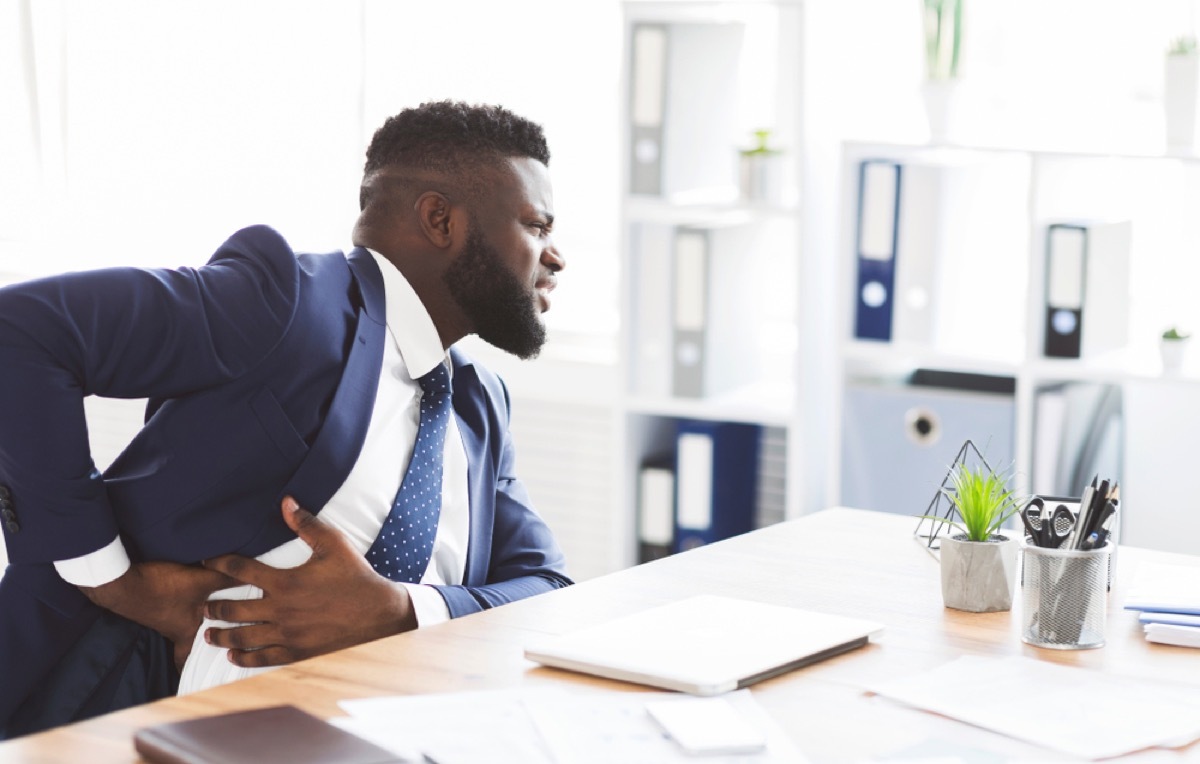 black man in suit clutching side in pain