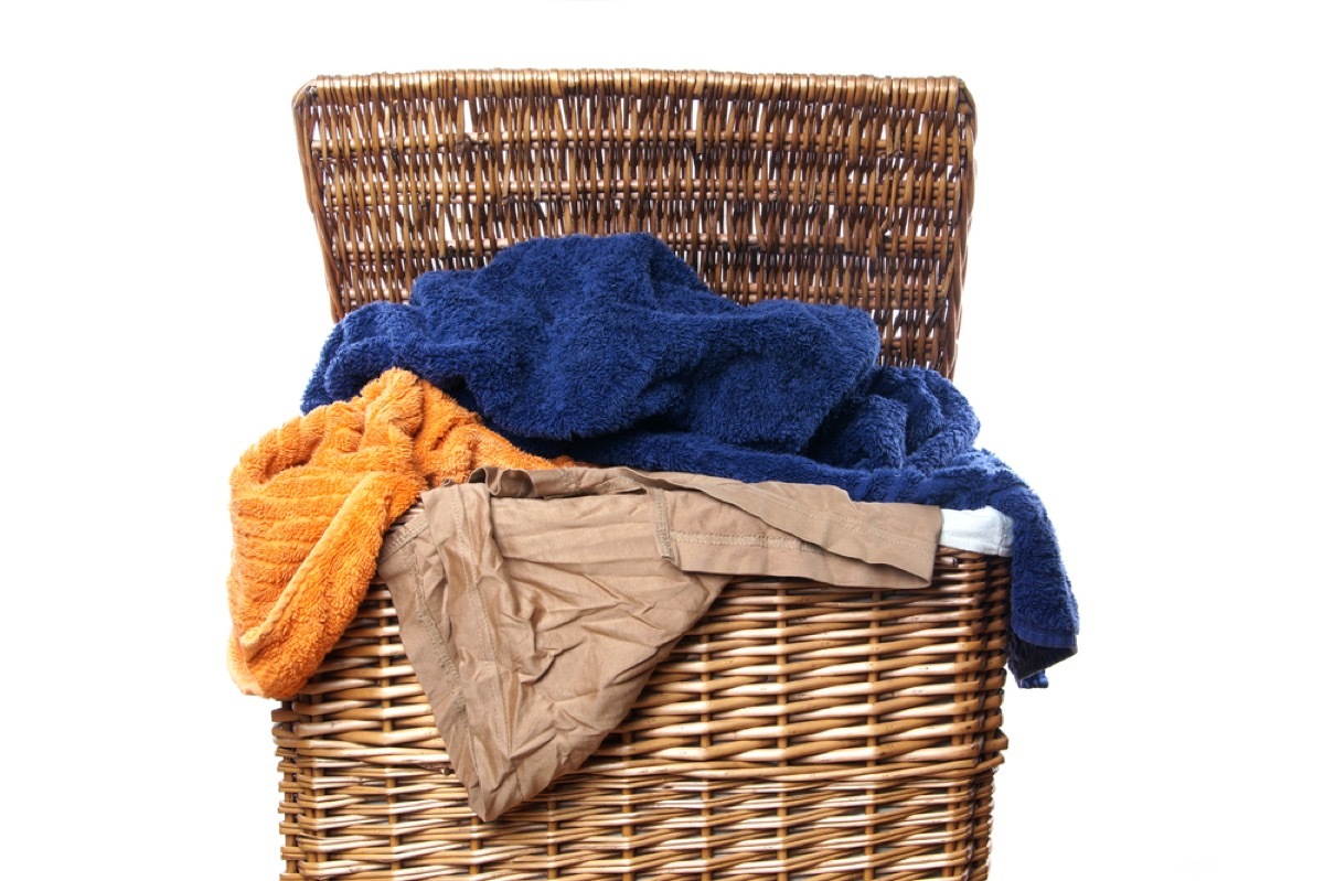 wicker hamper of dirty laundry on white background