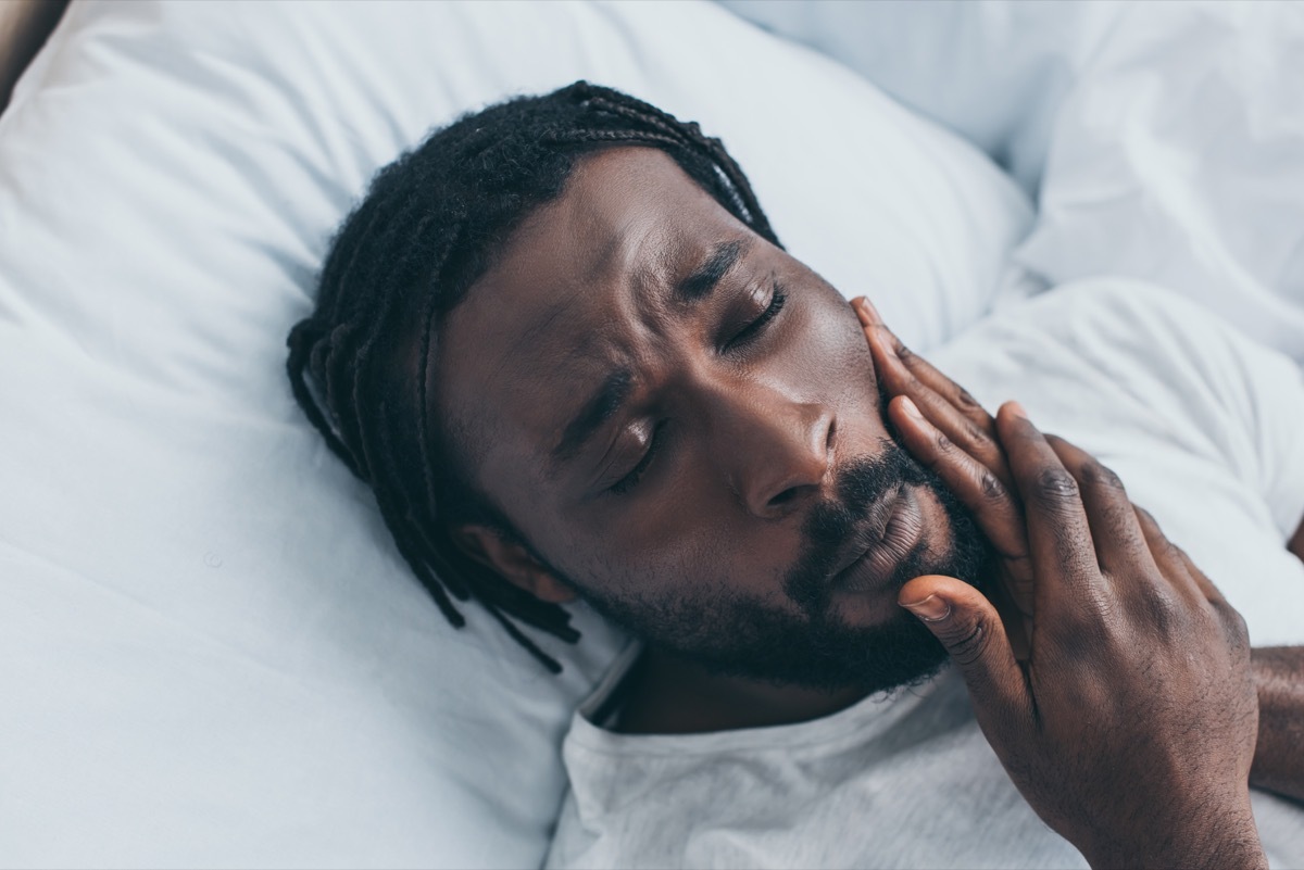 Man with jaw pain from grinding his teeth at night