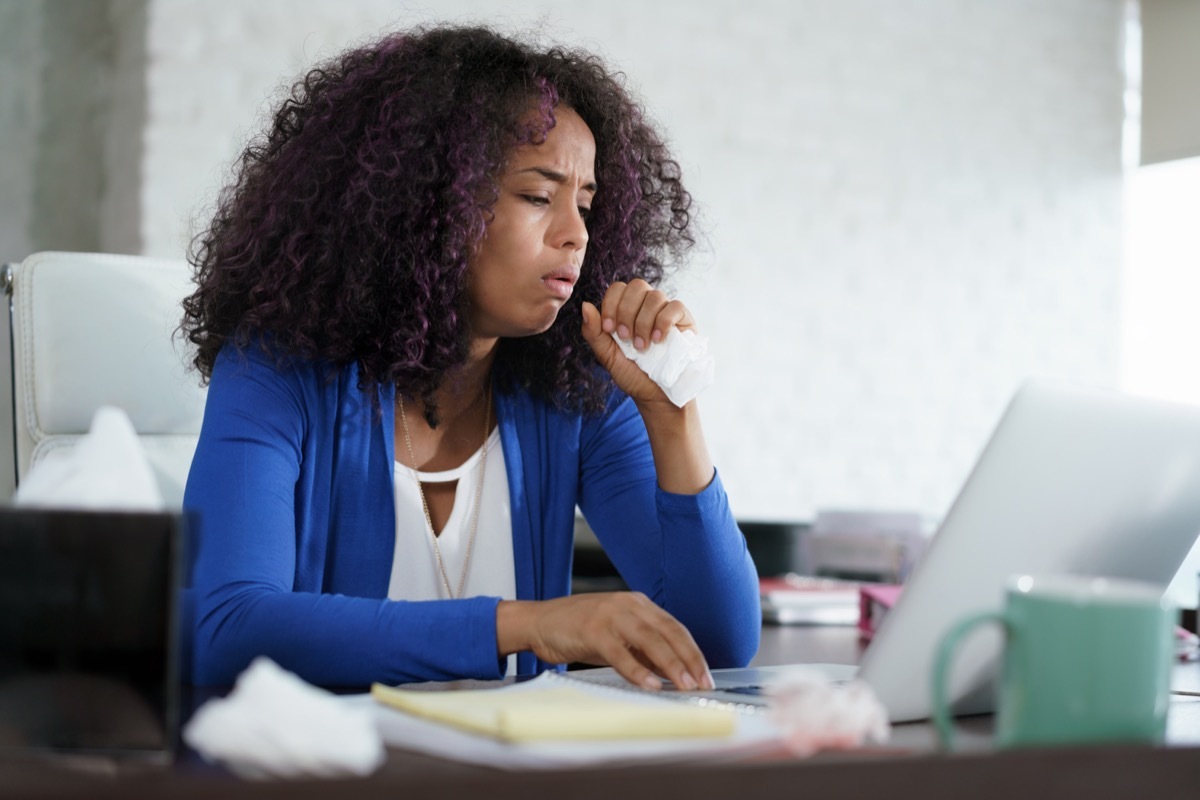 woman with cold, working on laptop computer, coughing and sneezing