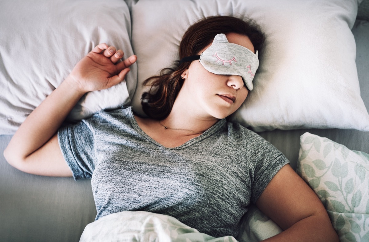 High angle shot of an attractive young woman sleeping with a mask on her face in her bedroom at home