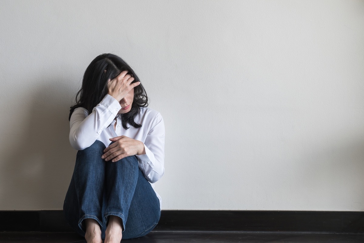 woman sitting on the ground covering her face with her hand