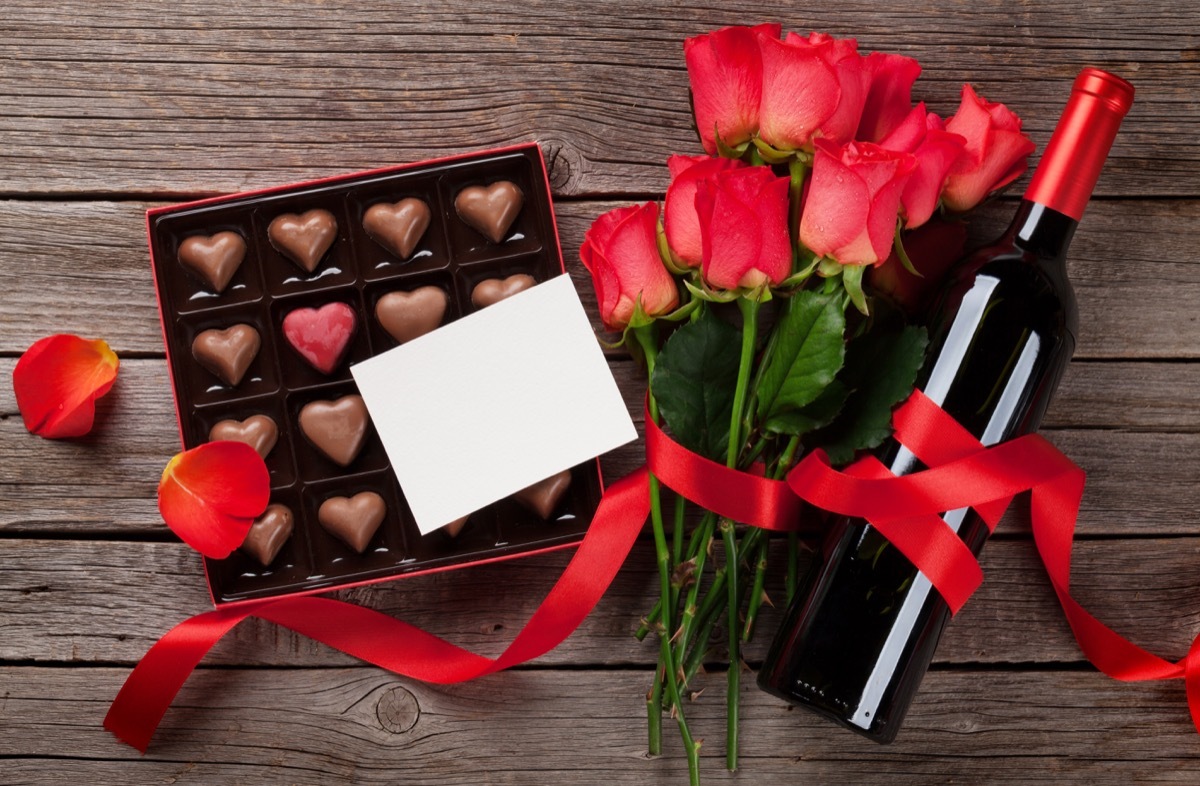 Valentines day with red roses, wine bottle and chocolate box on wooden table. Top view with space for your text - Image