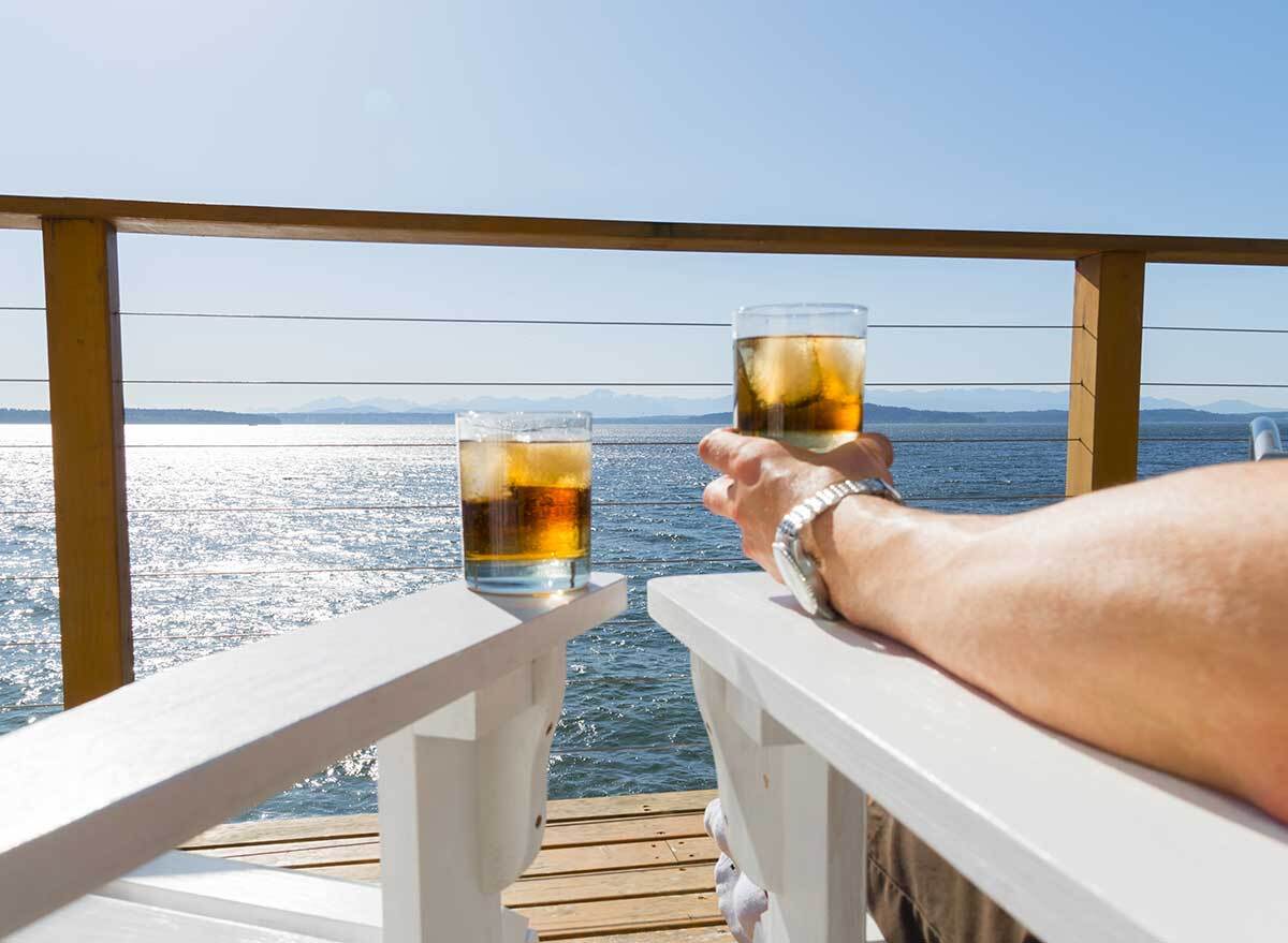 two whiskey glasses on cruise ship chairs overlooking ocean