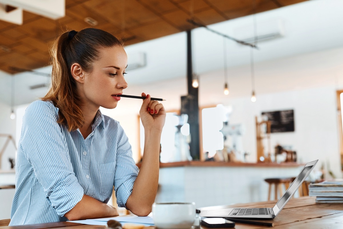 Freelancer Woman Using Laptop Computer Sitting At Cafe Table