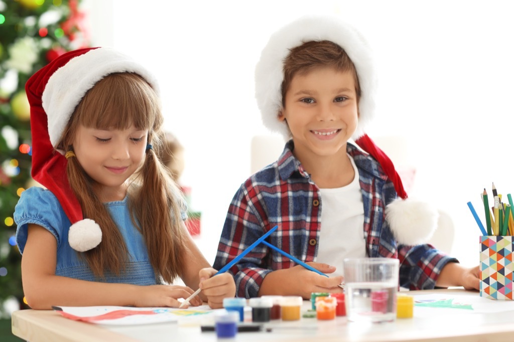 Little boy and girl wearing Santa hats and doing crafts