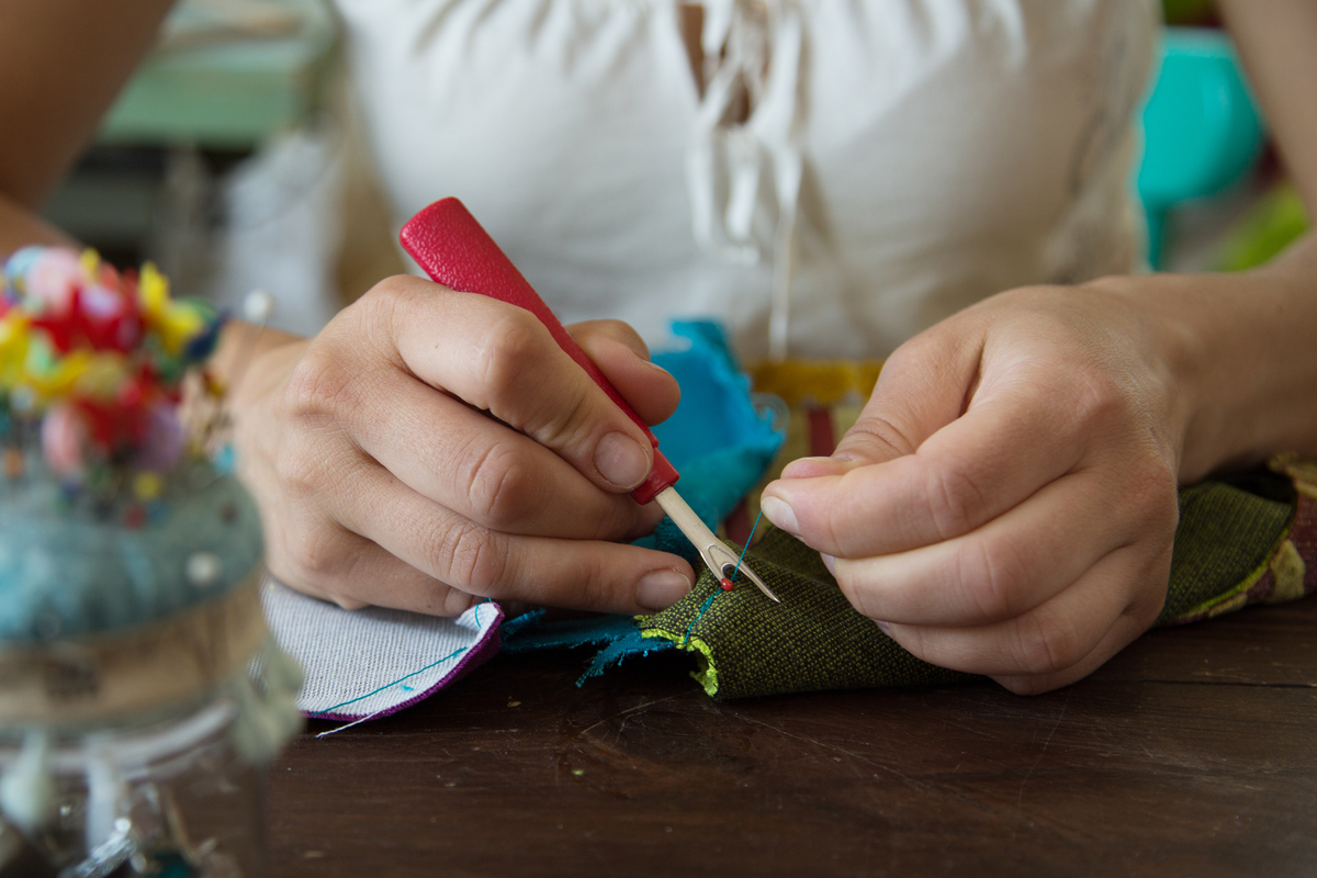 A female tailor stitching velvet pieces for a victorian chair reupholstery, home based business