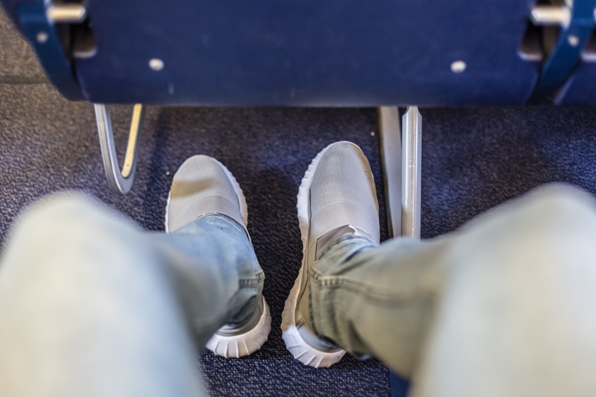 man's shoes underneath a plane seat