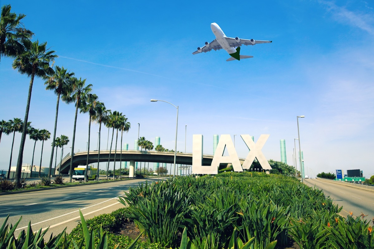 Los Angeles Airport sign full highway with airplane flying overhead.