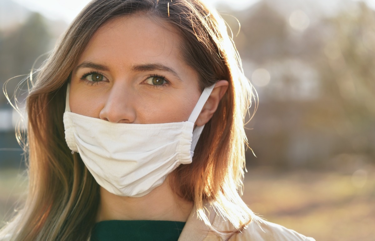 woman wears home made white cotton virus mouth face mask, wrong way, incorrect wearing